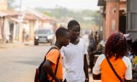 Young Beninese people in coloured clothes talk on the street. 123rf.com