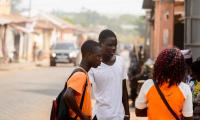 Young Beninese people in coloured clothes talk on the street. 123rf.com