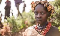 Ethiopia.  A girl from Dassanech tribe holds a little goat. She wears a beautiful hat made of beer caps. 123rf.com